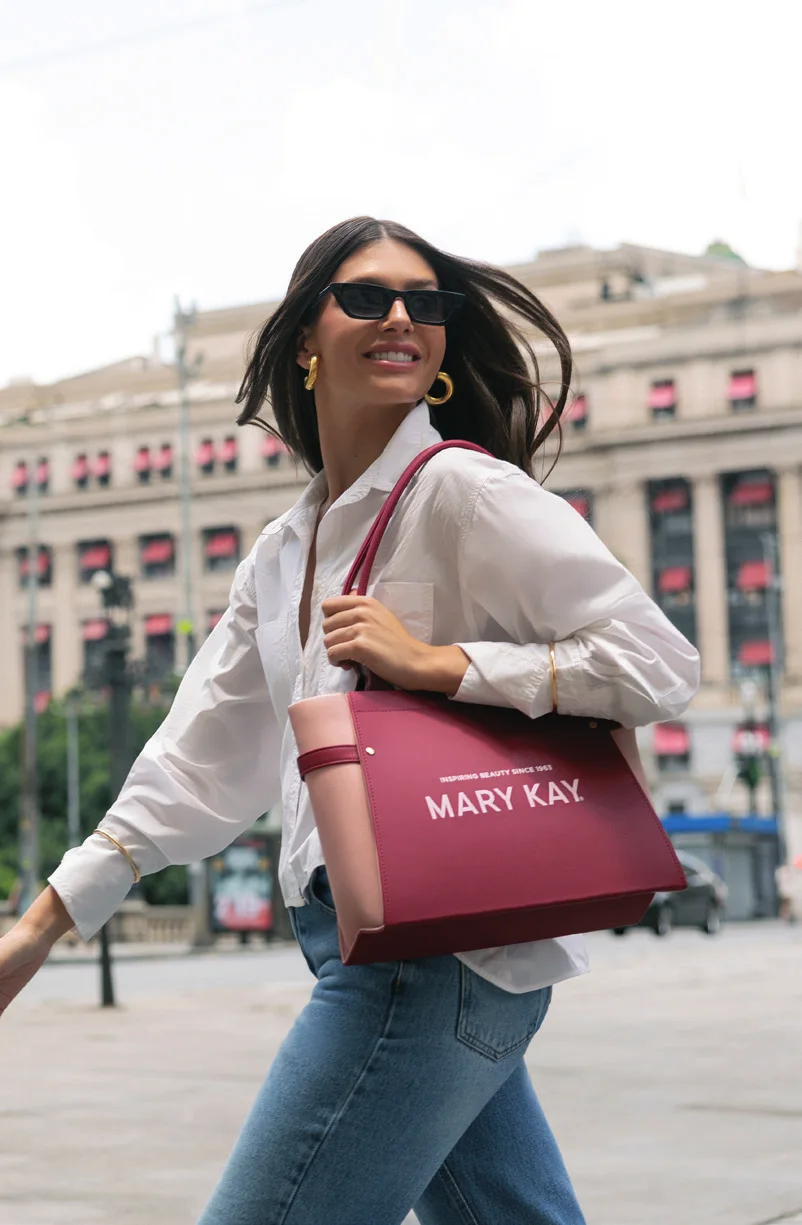 Mulher sorrindo na cidade com uma bolsa Mary Kay